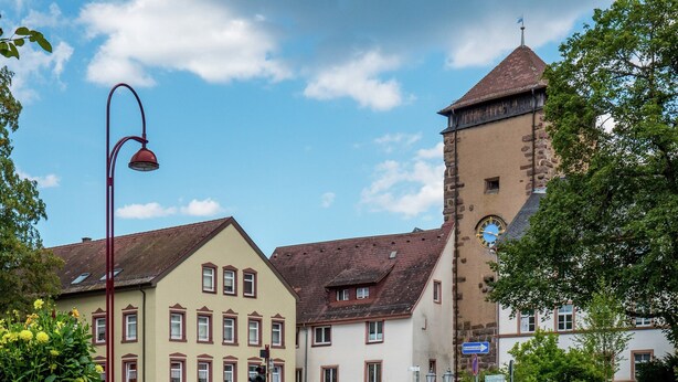 A building with a clock tower, a restaurant, and a flower garden. - Cozy Apartment in Schwenningen With Garden (Villingen-Schwenningen)