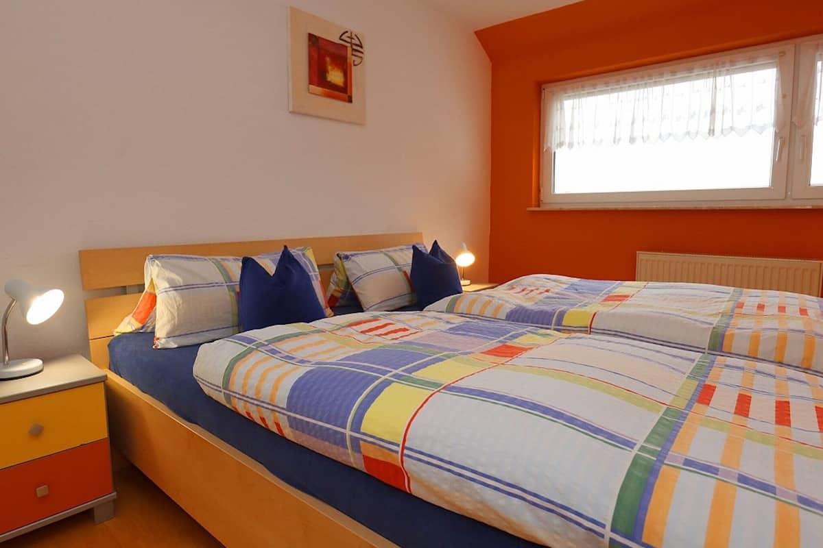 Una camera da letto con un letto, comodini, una finestra e un quadro appeso al muro.