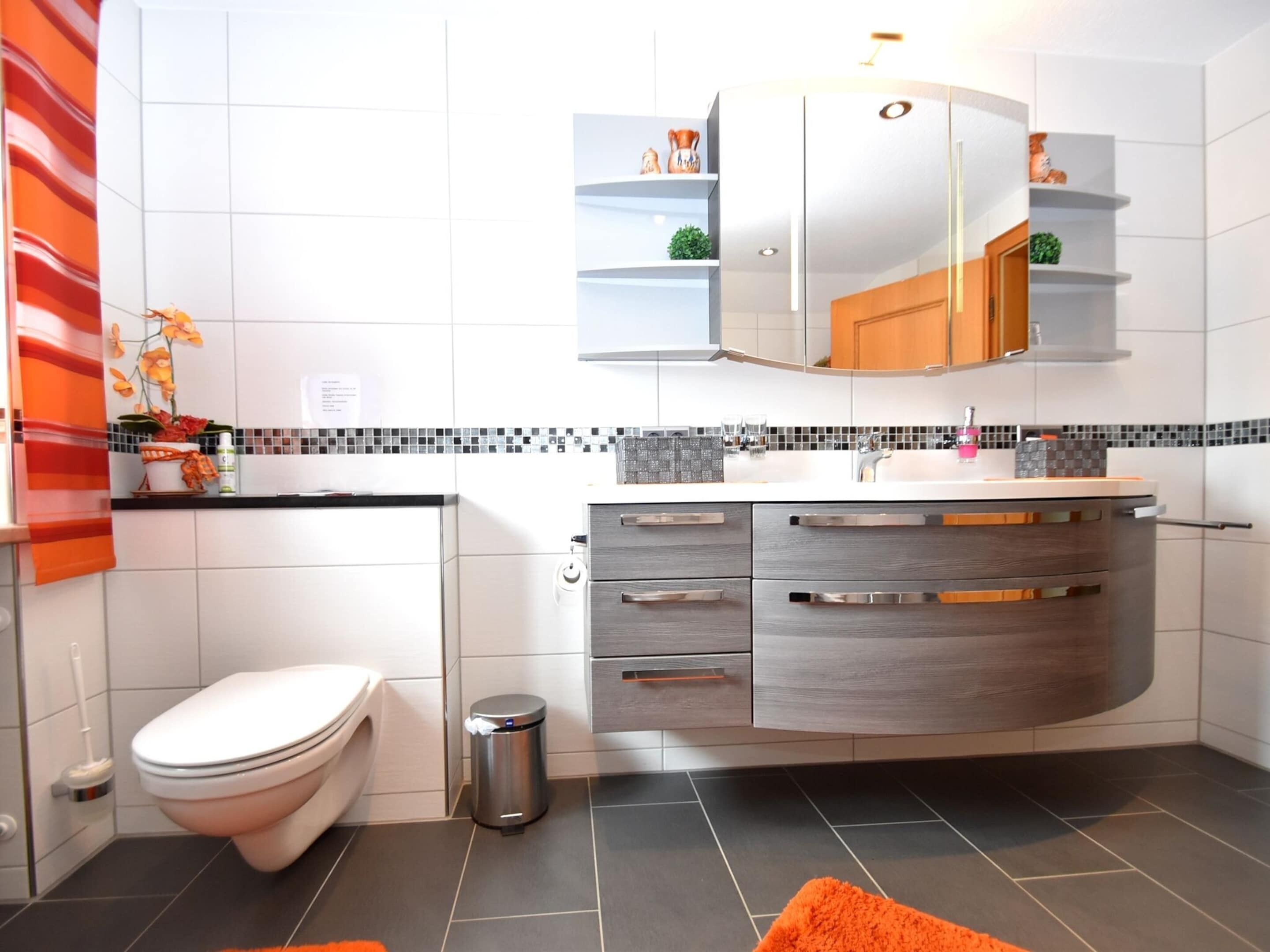 A modern bathroom with a toilet, sink, and vanity.