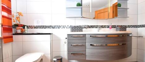 A modern bathroom with a toilet, sink, and vanity.