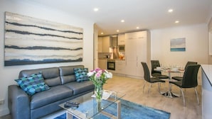 Un salon moderne avec un canapé, une table basse et un coin repas comprenant des chaises et une table mise pour le repas.