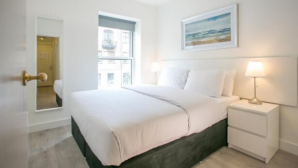 Une chambre à coucher avec un lit, des tables de chevet, une fenêtre et un tableau au mur.