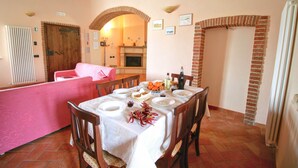 A dining area with a table set for four, a pink sofa, and a brick fireplace. - Lovely Farmhouse in Asciano With Swimming Pool (Asciano)
