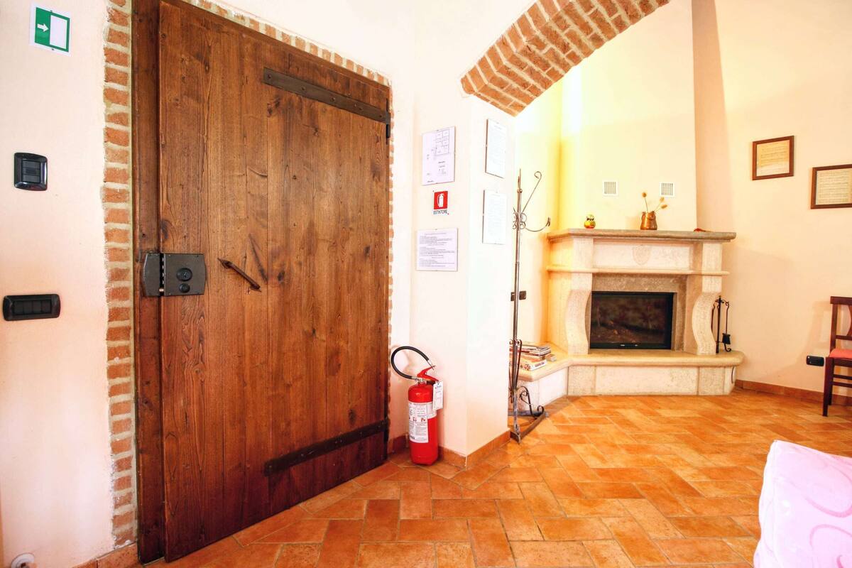 A room with a wooden door, a fire extinguisher, a fireplace, and a brick ceiling.