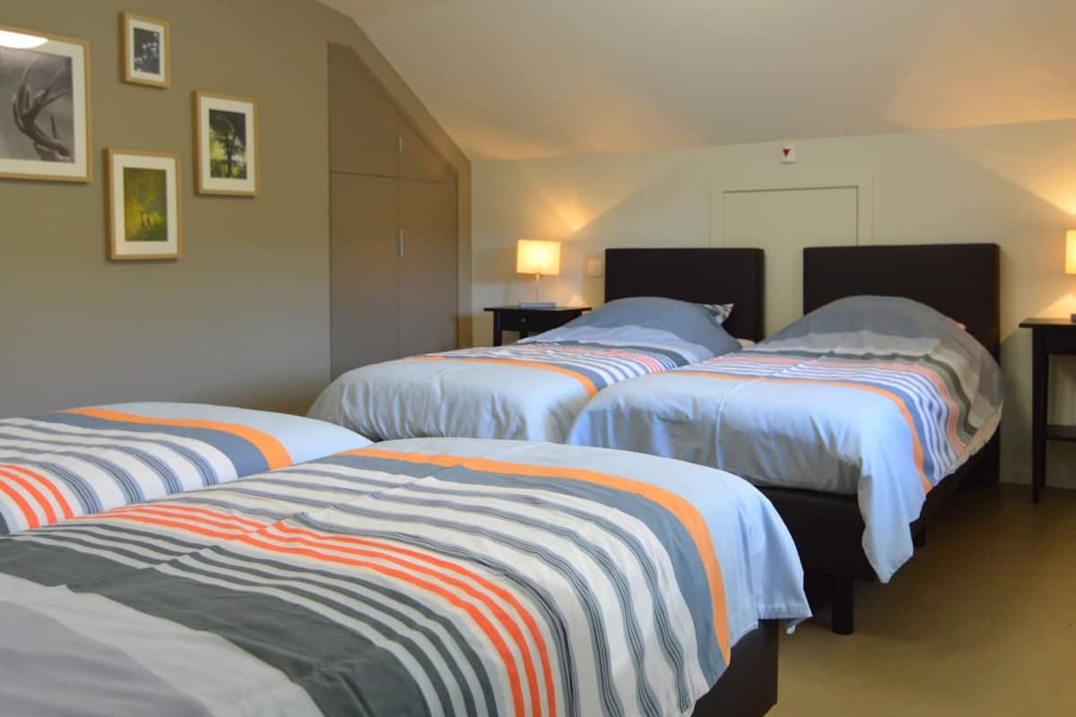 A hotel room with two beds, each with striped bedding, a nightstand with a lamp, and framed pictures on the wall.