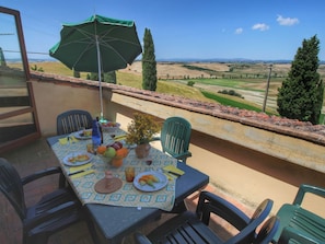 An outdoor dining area with a table set for two, a green umbrella, and a view of the countryside. - Traditional Farmhouse in Toscana With Swimming Pool (Asciano)