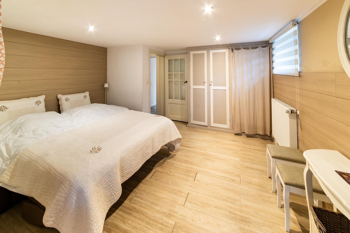 A bedroom with a bed, a desk, and a chair.