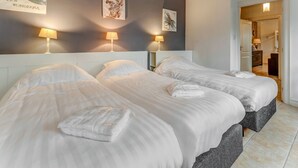 A hotel room with two beds, a large mirror, and artwork on the walls.