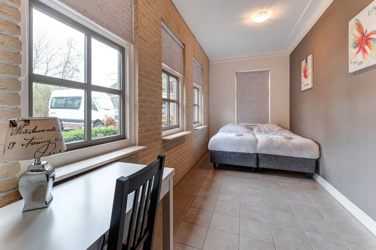Ein Schlafzimmer mit Bett, Fenster und Tisch mit Stuhl.