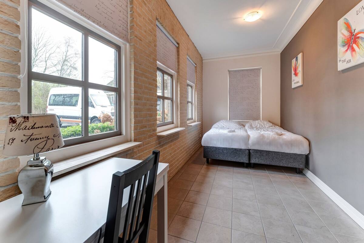 A bedroom with a bed, a window, and a table with a chair.