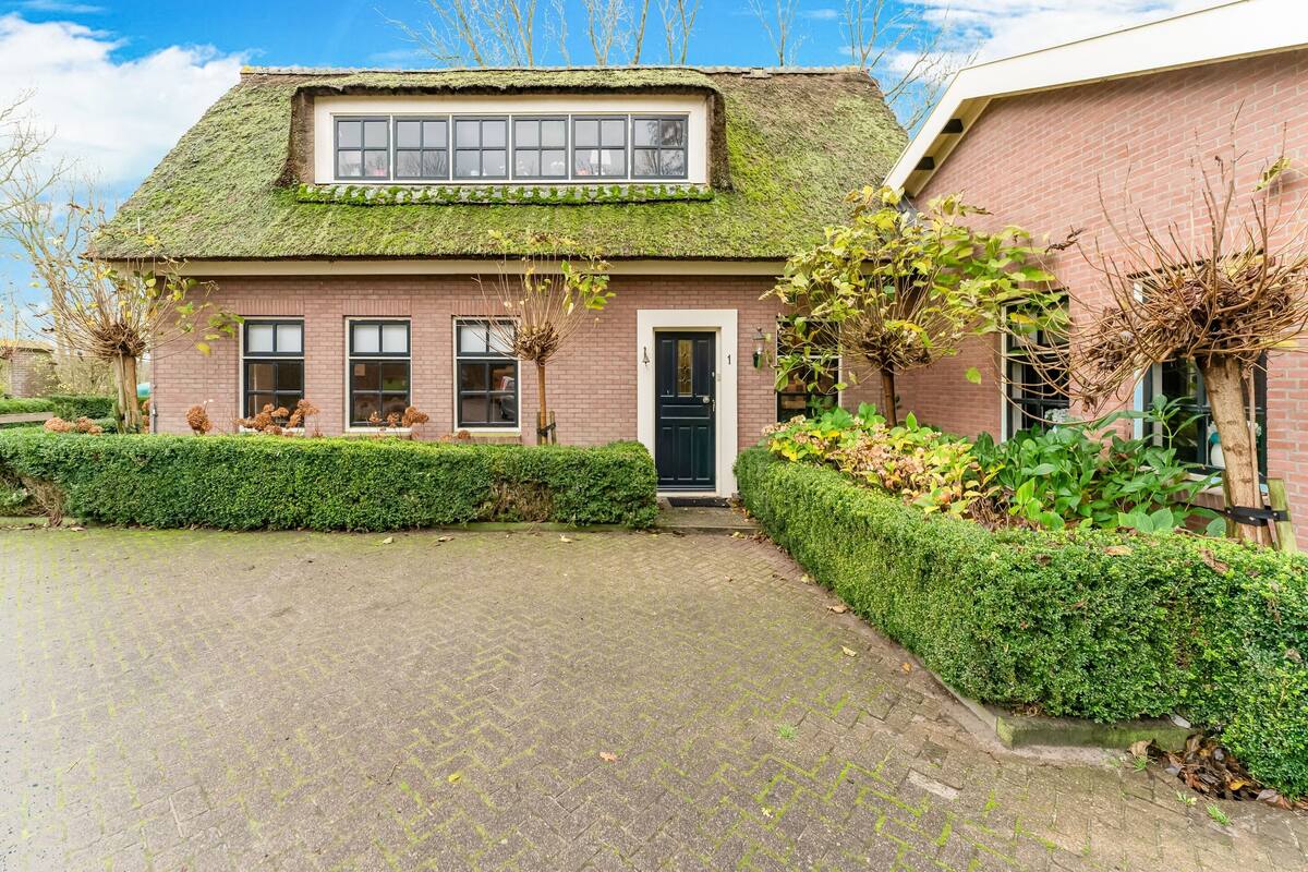 A house with a moss-covered roof, a black door, and a brick exterior.