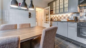 A modern kitchen with grey cabinets, a wooden dining table, and three pendant lights.