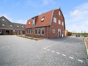 Een modern gebouw met een bakstenen gevel, grote ramen en een bestraat binnenterrein.