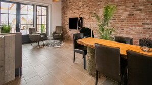 A modern dining area with a brick wall, wooden beams, and a large window. - Spacious Holiday Home Hazenborgh in Callantsoog Near Beach (Callantsoog)
