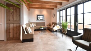A spacious living room with a wooden ceiling, a large window, and a cozy seating area with a sofa and chairs. - Spacious Holiday Home Hazenborgh in Callantsoog Near Beach (Callantsoog)