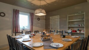 A dining room with a wooden table set for six, surrounded by chairs, with a hanging light fixture above. - Luxury Holiday Home in Thirimont Liege With Private Garden (Waimes)