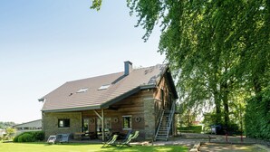 A rustic wooden house with a sloped roof, a porch with outdoor seating, and a well-maintained lawn. - Luxury Holiday Home in Thirimont Liege With Private Garden (Waimes)