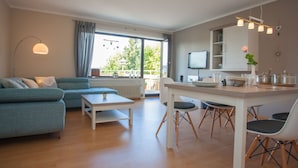 A modern living room with a sofa, coffee table, and dining area with chairs and a table. - Large Apartment Near Ski Area in Winterberg Germany (Winterberg)