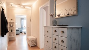 A hallway with a white dresser, a mirror, and a vase with flowers. There is a bench and a door leading to another room. - Large Apartment Near Ski Area in Winterberg Germany (Winterberg)