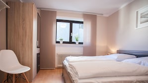 A bedroom with a bed, a chair, a radiator, and a window with plants. - Large Apartment Near Ski Area in Winterberg Germany (Winterberg)