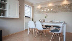A modern kitchen with white cabinetry, a stone accent wall, and pendant lighting. - Large Apartment Near Ski Area in Winterberg Germany (Winterberg)