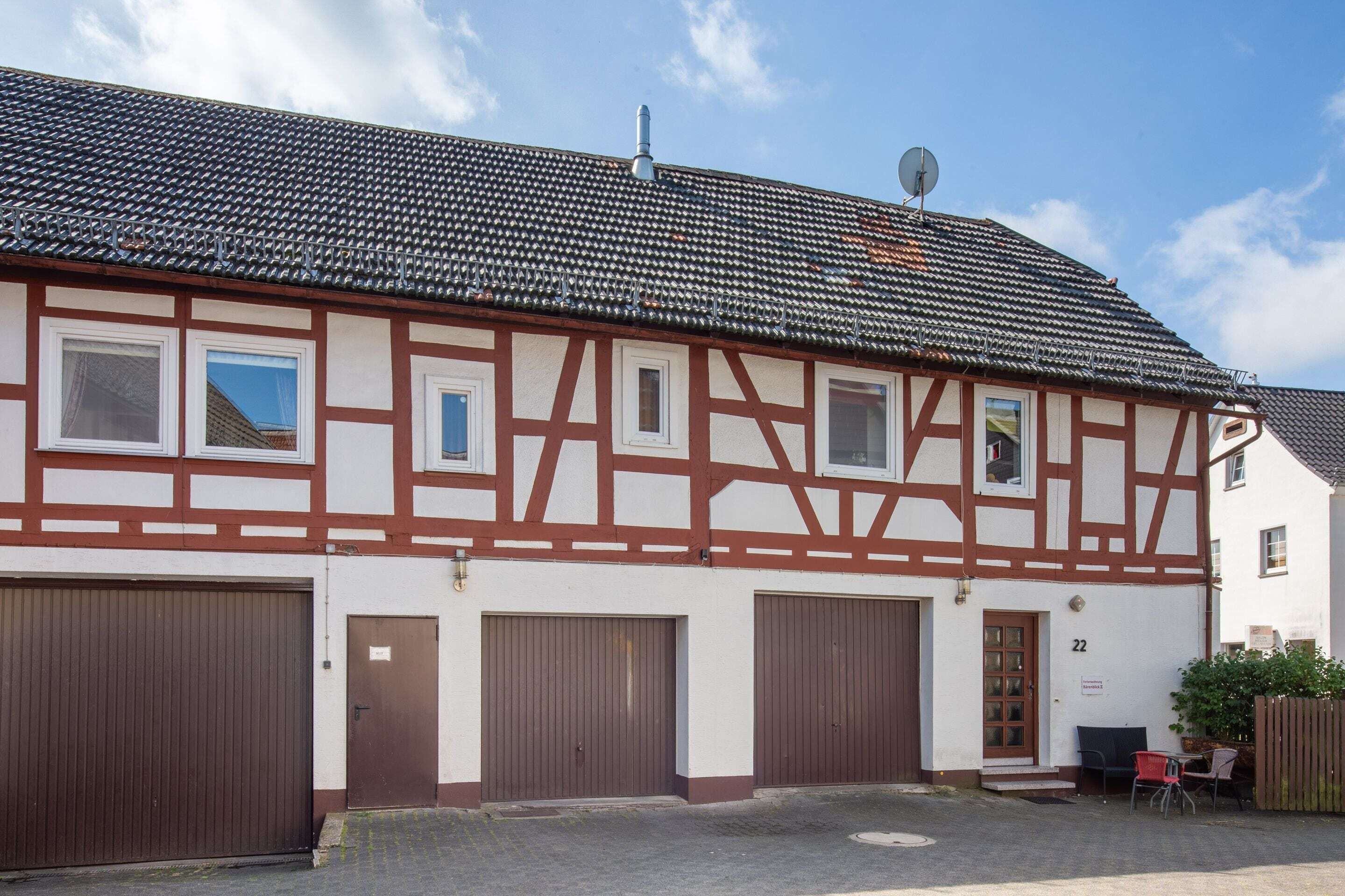 A traditional half-timbered building with three garage doors and a small outdoor seating area.