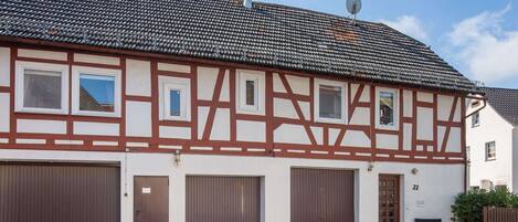 A traditional half-timbered building with three garage doors and a small outdoor seating area.