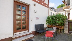 Un bâtiment portant le numéro 22, avec une porte en bois et un petit espace extérieur aménagé avec une table et des chaises.