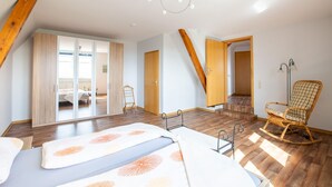 Une chambre spacieuse avec un grand lit, un fauteuil à bascule et une armoire.