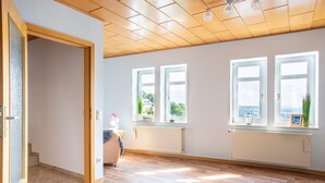 Une pièce spacieuse dotée d’un plancher en bois, de grandes fenêtres et offrant une vue sur l’extérieur.