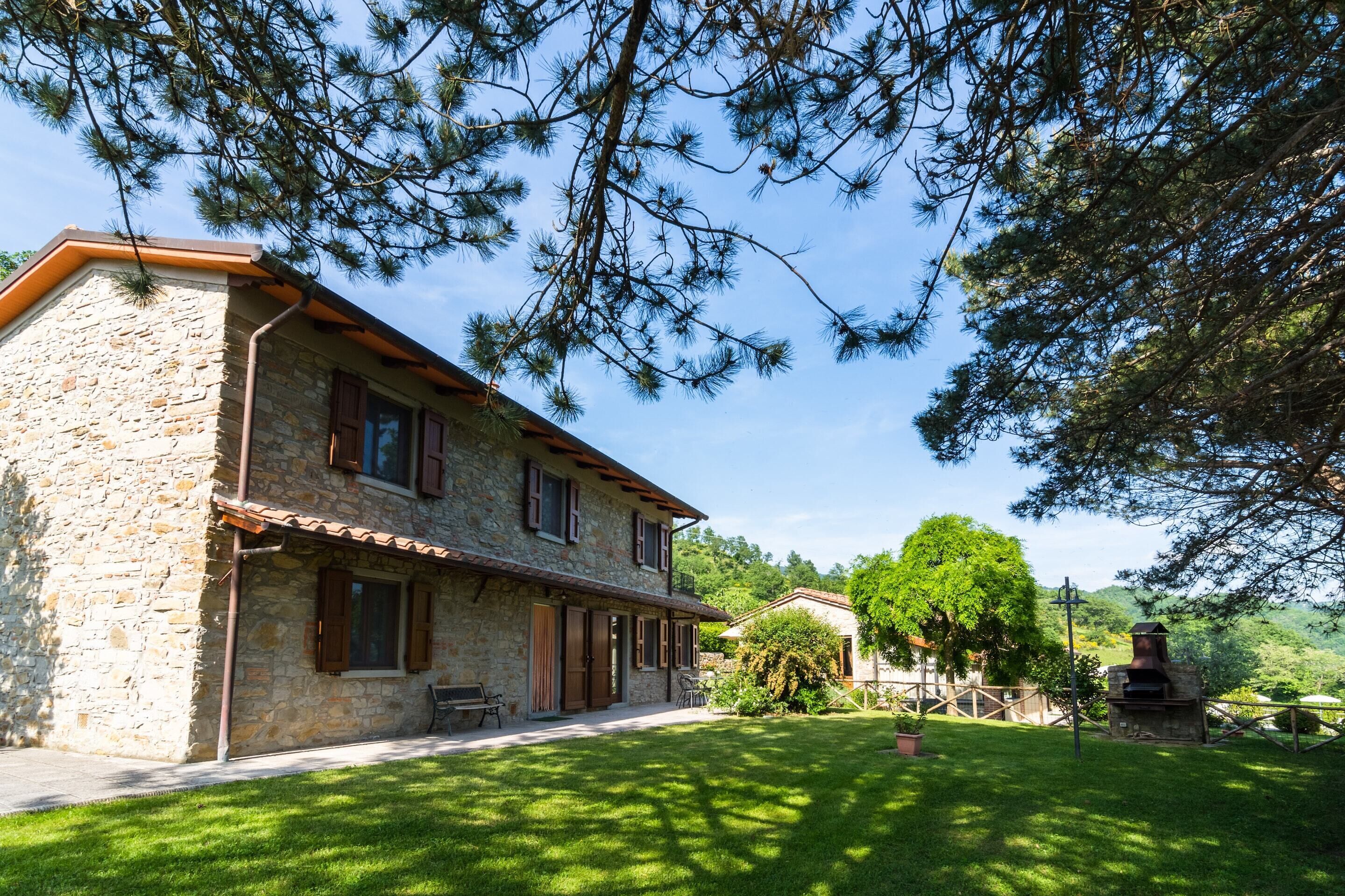 A stone house with a tiled roof, a patio, and a barbecue area.