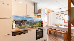A modern kitchen with white cabinets, a built-in oven, and a large window overlooking a scenic landscape. - Detached Modern Holiday Home With Sauna in the Salzburgerland (Bruck an der Grossglocknerstrasse)