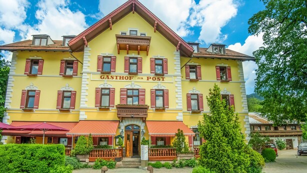 A yellow building with red shutters and a sign reading "GASTHOF ZUR POST". - Detached Modern Holiday Home With Sauna in the Salzburgerland (Bruck an der Grossglocknerstrasse)