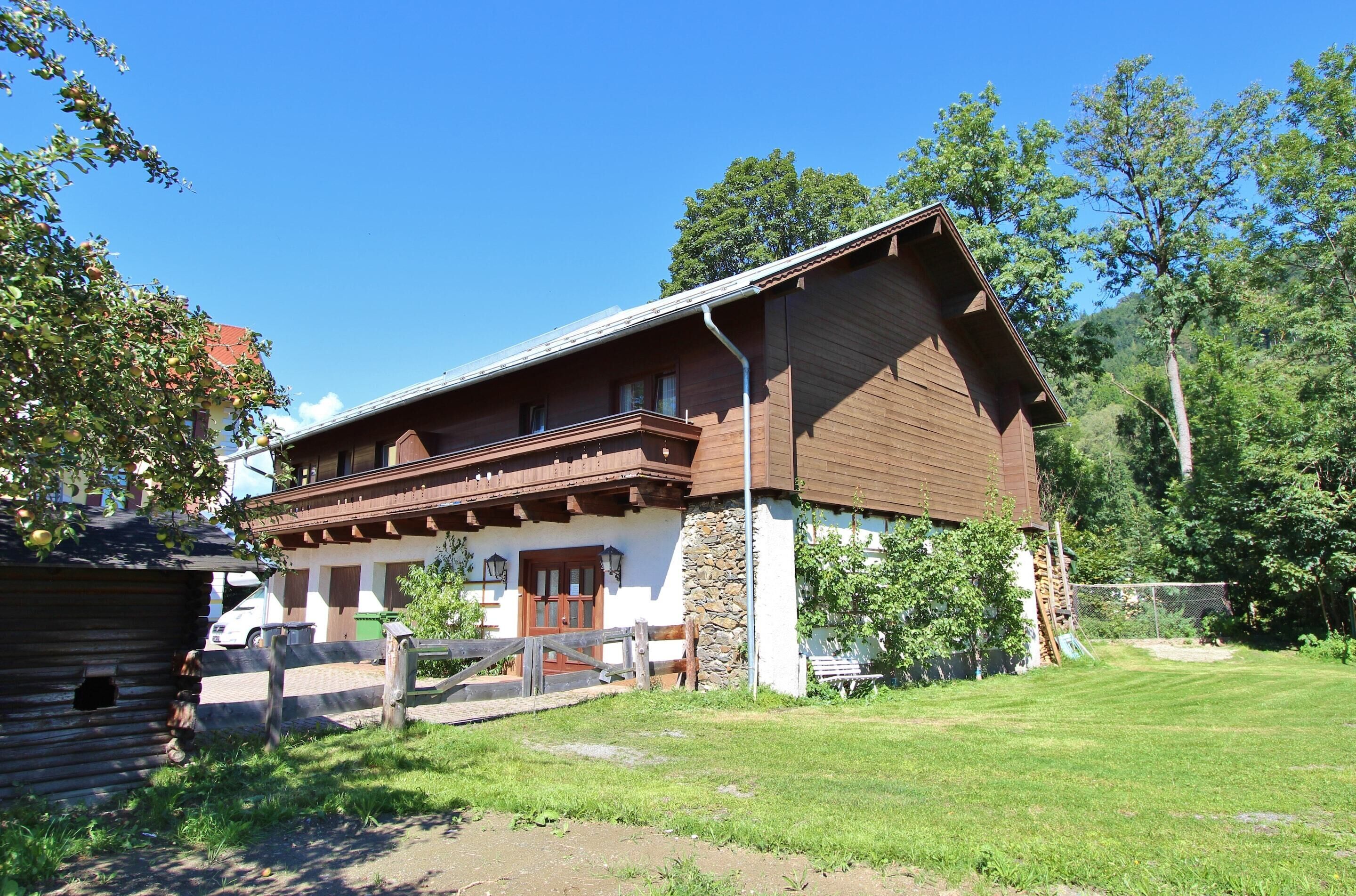 Une maison traditionnelle en bois, avec un toit en pente, des fondations en pierre et une véranda à l’avant.