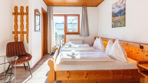A wooden bed with white linens, a wooden headboard, and a glass table with a chair. - Detached Modern Holiday Home With Sauna in the Salzburgerland (Bruck an der Grossglocknerstrasse)
