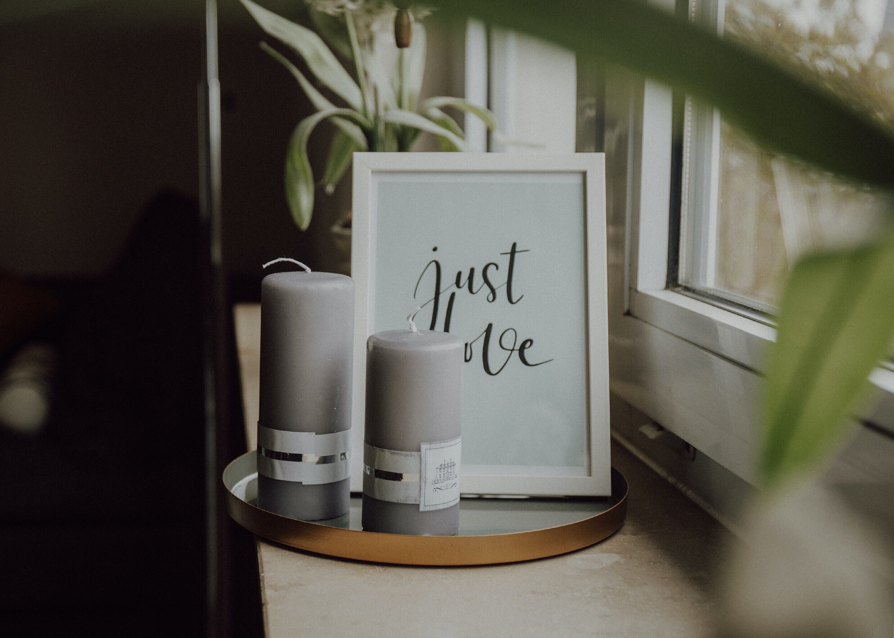 A framed sign with the text "Just love" and two candles on a tray.