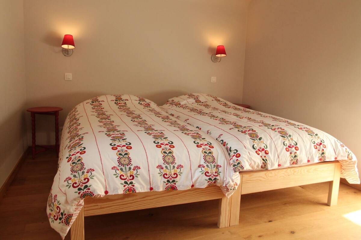 A bedroom with a wooden bed, floral-patterned bedding, and two wall-mounted lamps.
