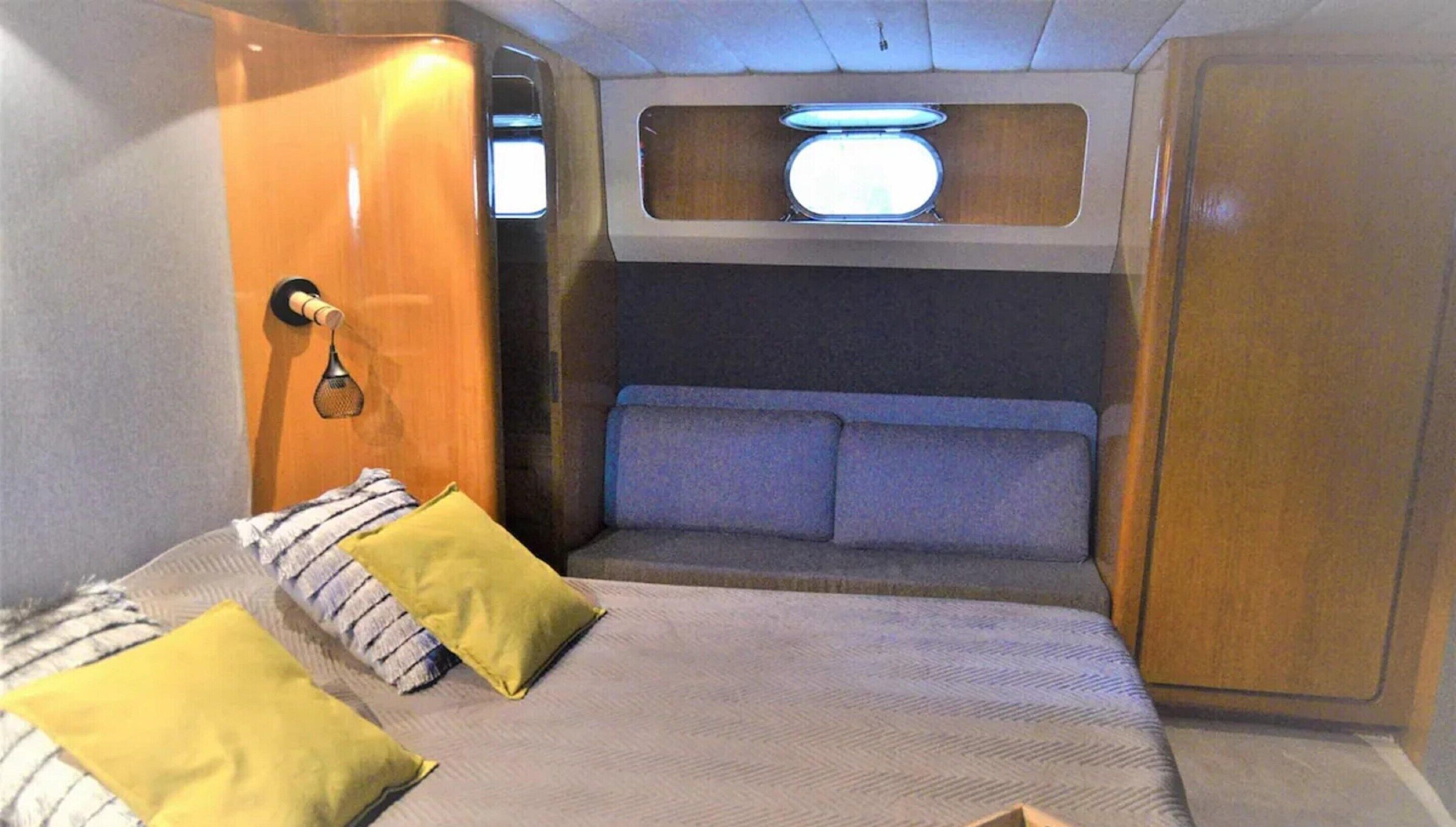 A compact RV bedroom with a bunk bed, a small window, and a door.