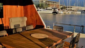 A dining area with a wooden table and chairs, overlooking a marina with boats. - Luxury Yacht in La Rochelle With a Terrace (La Rochelle)