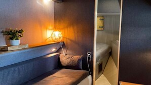 A compact, modern interior with a cushioned bench, a bedside table with a lamp, and a small potted plant. - Luxury Yacht in La Rochelle With a Terrace (La Rochelle)
