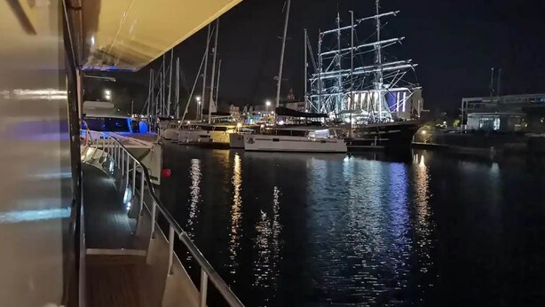 A nighttime marina with multiple sailboats docked, a well-lit waterfront, and a covered walkway. - Luxury Yacht in La Rochelle With a Terrace (La Rochelle)
