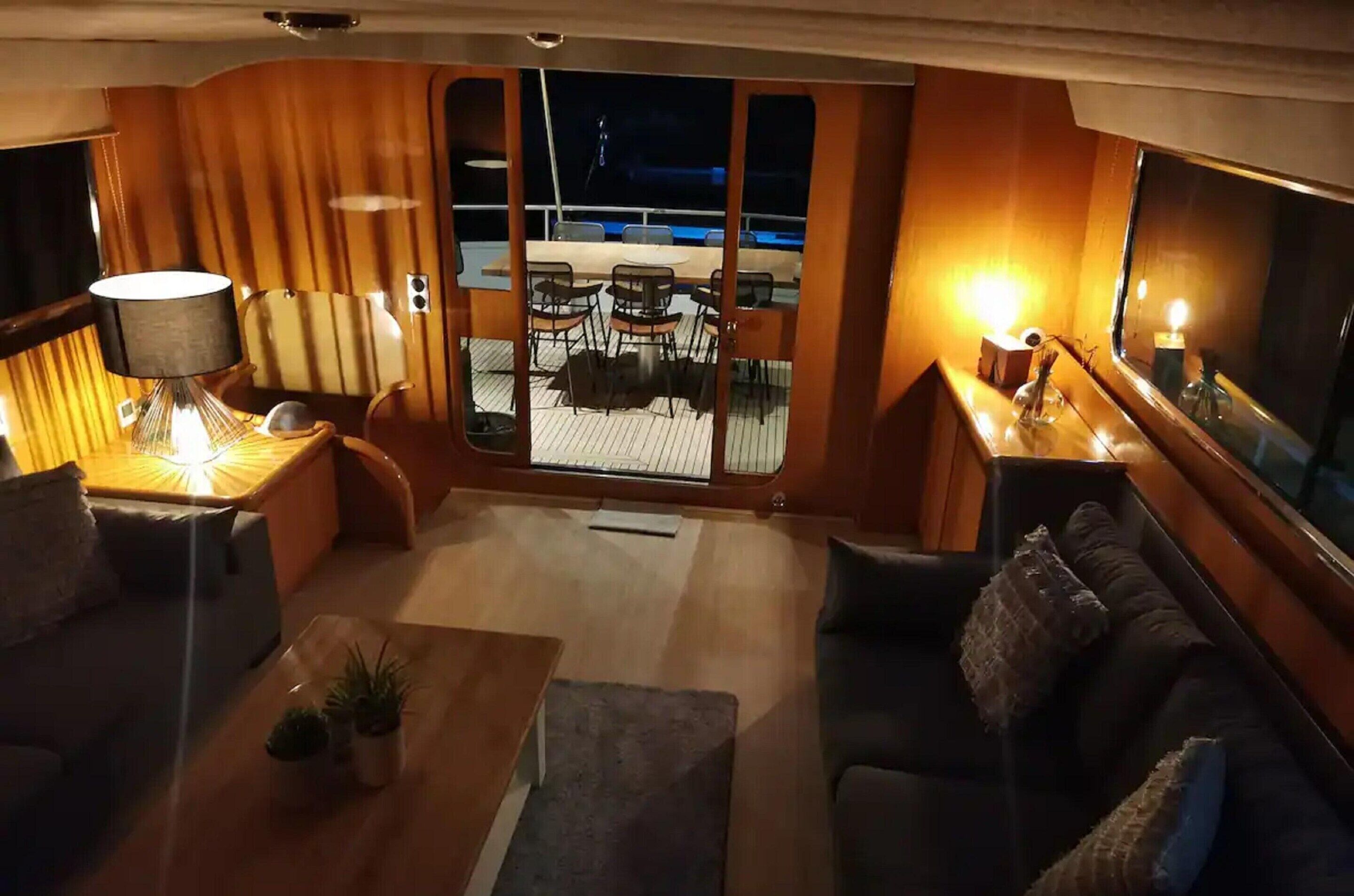 Un interior acogedor con una terraza de madera, una zona de comedor con sillas, un sofá y una lámpara.