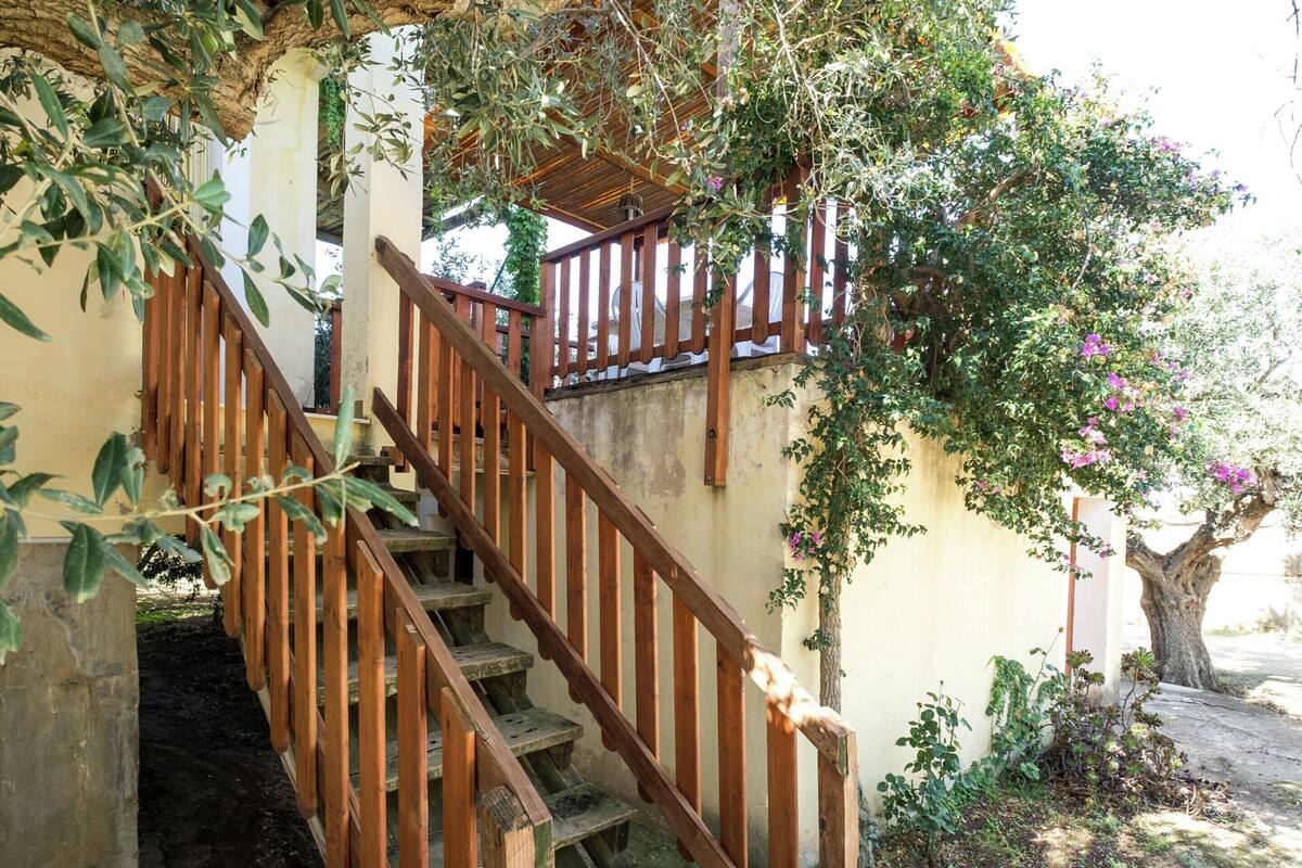 A wooden staircase with a railing, leading to a covered area with a wooden roof.