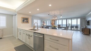 Une cuisine moderne avec des meubles blancs, un îlot central et un coin repas offrant une vue agréable.