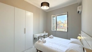 Une chambre d’hôtel avec un lit, un bureau et une fenêtre donnant sur la ville.