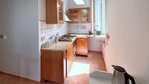 Une cuisine avec des meubles de rangement en bois, une cuisinière à gaz et une fenêtre qui laisse entrer la lumière naturelle.