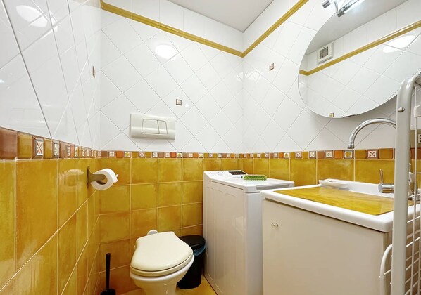 Une petite salle de bain comprenant des toilettes, un lave-linge et un lavabo.