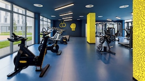 Une salle de sport moderne équipée de machines de cardio, d’appareils de musculation et de grandes fenêtres offrant une vue sur l’extérieur.