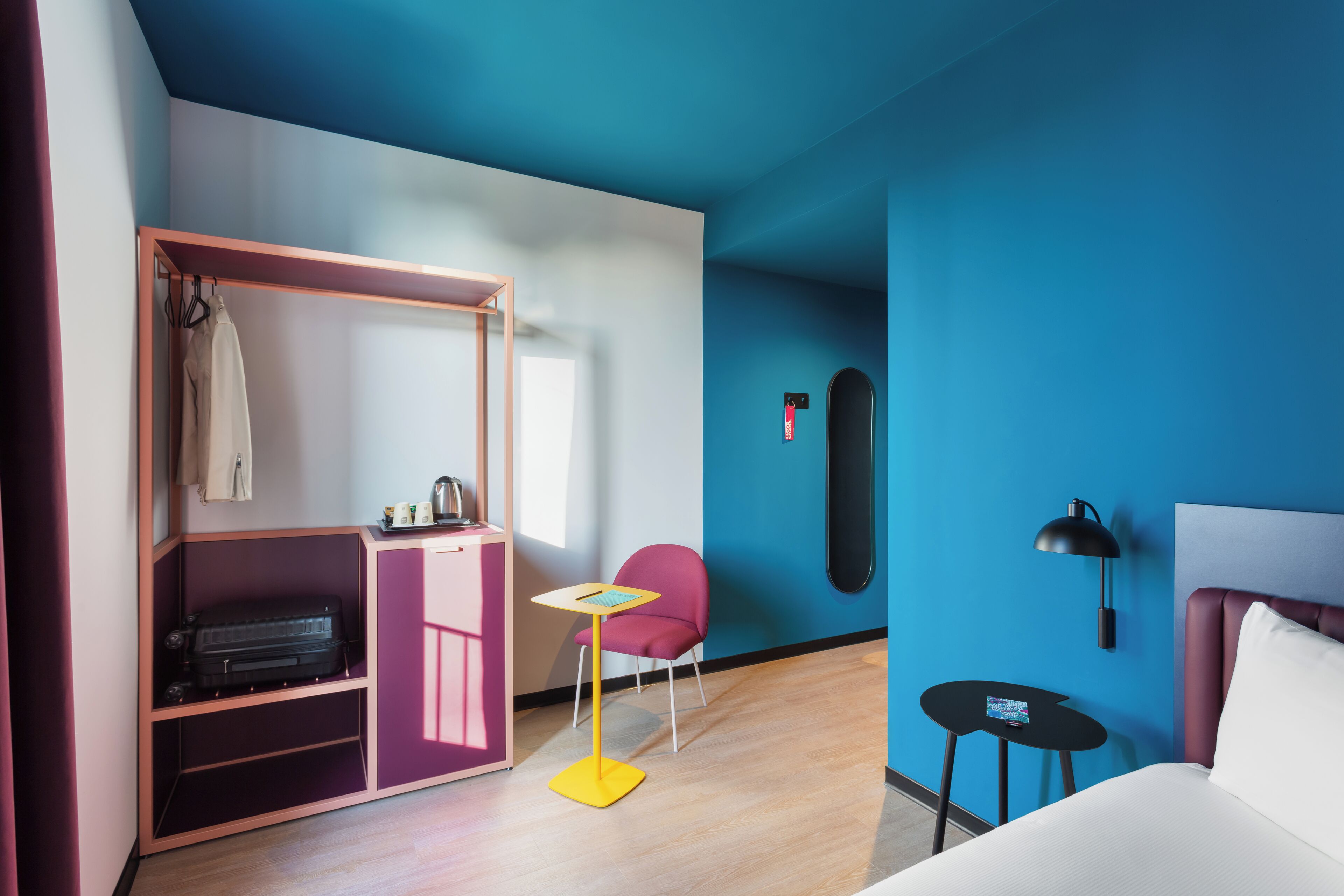 Una habitación con cama, escritorio, silla, armario y un objeto montado en la pared.