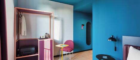 A room with a bed, a desk, a chair, a wardrobe, and a wall-mounted item.